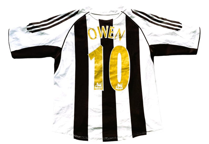 May include: A white and black striped soccer jersey with gold lettering. The name "OWEN" and the number "10" are on the back of the jersey.