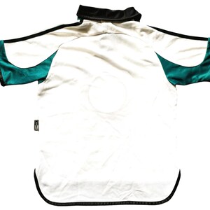 May include: White short-sleeved jersey with black trim and green accents on the sleeves.