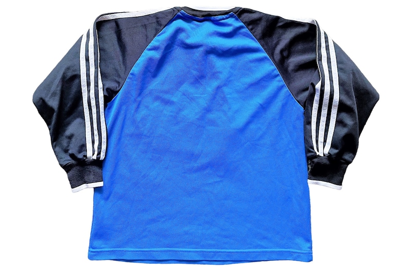 May include: A blue long-sleeve shirt with black and white striped sleeves. The shirt has a raglan design and a crew neck.