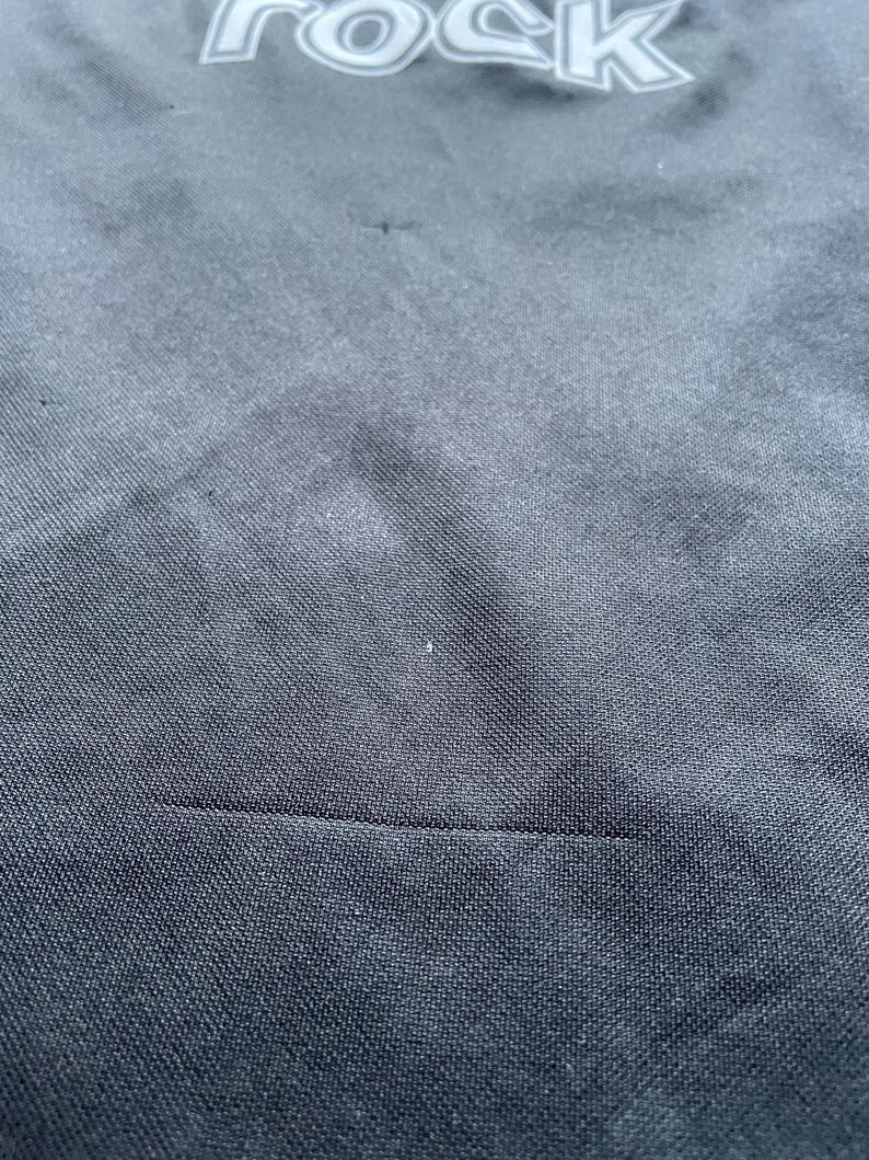 May include: Close-up of a black fabric with a subtle texture. The fabric has a seam running horizontally across the bottom of the image.