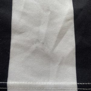 May include: Close-up of a fabric with a vertical black and white striped pattern. The white stripe has a textured appearance, and a seam runs horizontally across the bottom of the image.