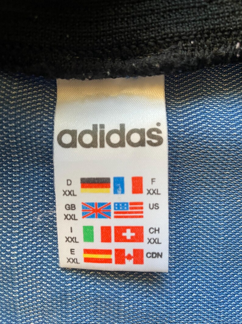 May include: White tag with black text "adidas" and size chart in multiple languages. The tag shows sizes for Germany, Great Britain, Italy, Spain, Switzerland, the United States, and Canada.
