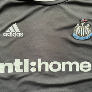May include: Black soccer jersey with white Adidas logo, Newcastle United crest, and "ntl:home" text.