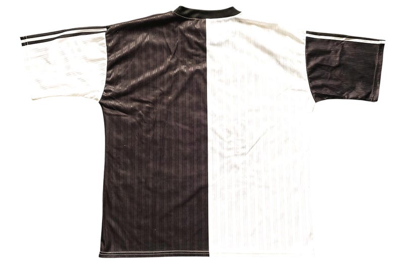May include: A two-tone sports jersey, split vertically with a dark brown and white design. The jersey has a black collar and sleeve cuffs with white stripes. The fabric has a subtle ribbed texture.