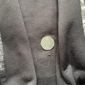 May include: Black fabric with silver stripes. The fabric has a small hole in the centre.