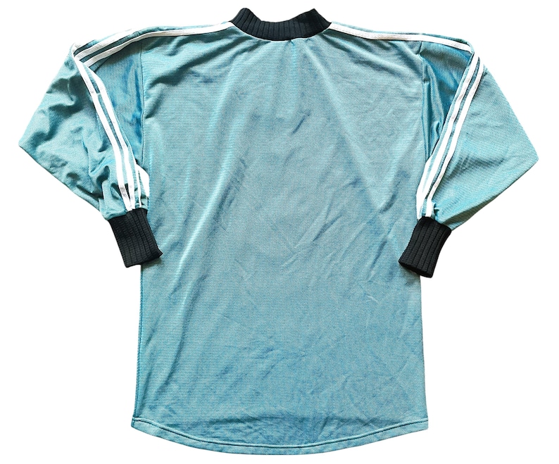 K&ouml;nnte beinhalten: Ein tealfarbenes Langarmshirt mit wei&szlig;en Streifen auf den &Auml;rmeln und einem schwarzen Kragen und B&uuml;ndchen. Das Shirt hat ein sportliches Design und eine gerippte Textur.