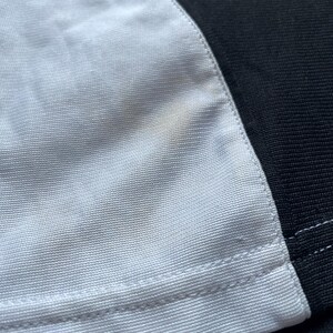 May include: A white and black fabric with a seam down the center. The white fabric has a slight yellow stain.