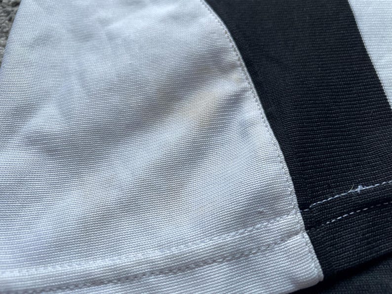 May include: A white and black fabric with a seam down the center. The white fabric has a slight yellow stain.
