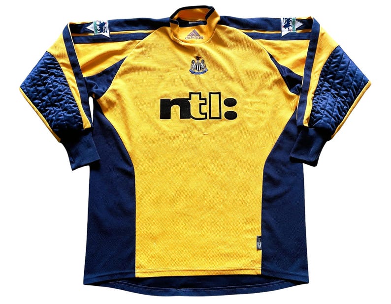 May include: Yellow and blue long-sleeved soccer jersey with the Newcastle United crest and the NTL logo.