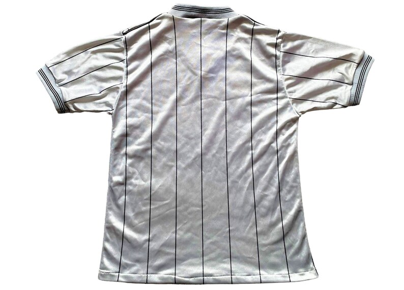 May include: White striped soccer jersey with a black collar and black trim on the sleeves.