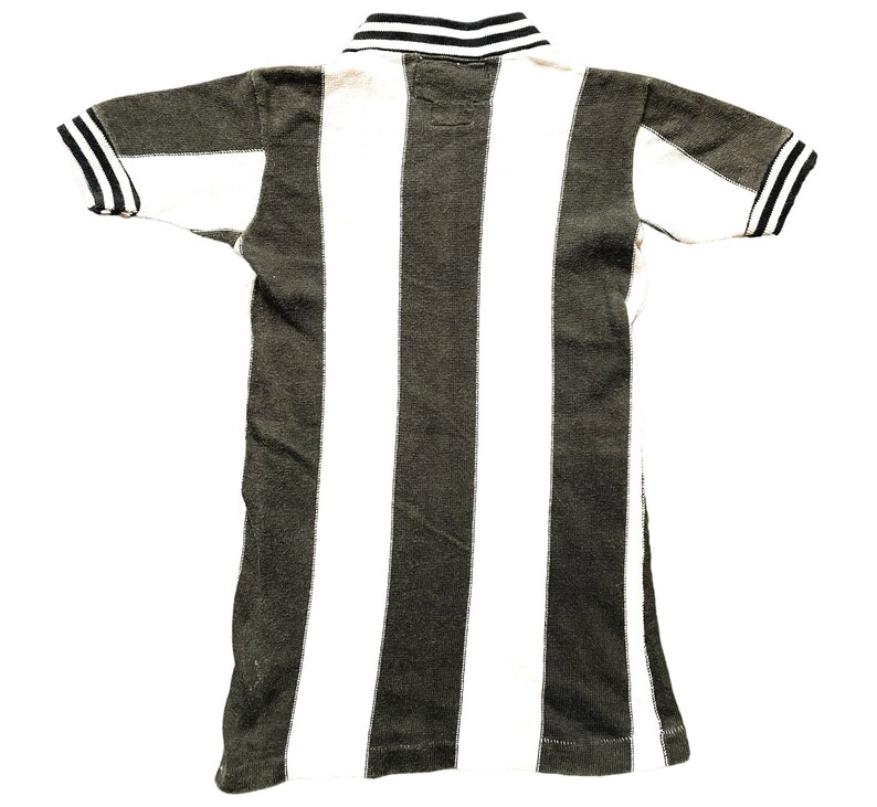 Puede incluir: Una camiseta polo de rayas blancas y negras con cuello negro y ribetes negros en las mangas.