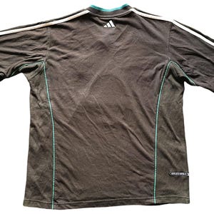 May include: A black t-shirt with white and teal trim. The shirt has a small Adidas logo on the back.
