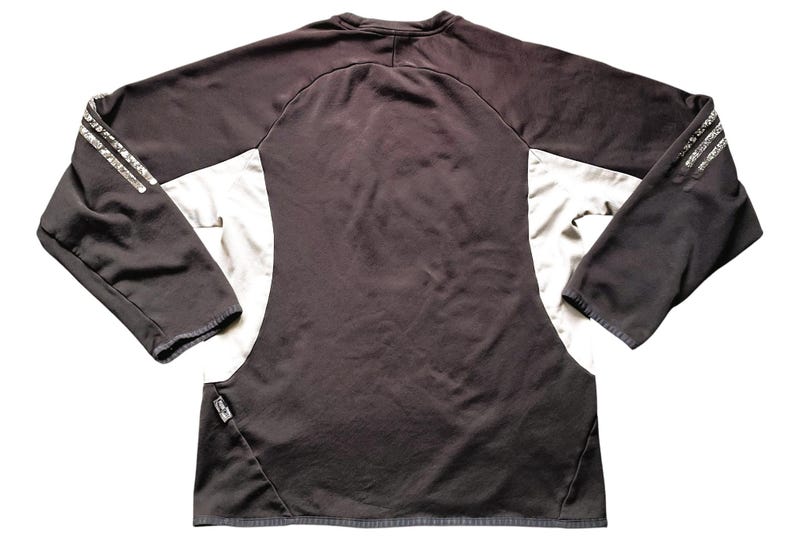 May include: Black and white long-sleeved athletic shirt with a silver stripe detail on the sleeves. The shirt has a crew neck and a fitted silhouette.