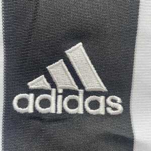 May include: A white adidas logo with three stripes embroidered on a black fabric background.
