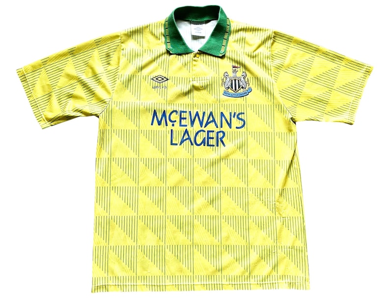 May include: A yellow and green soccer jersey with a black and white team logo and the text "McEWAN'S LAGER" on the front.