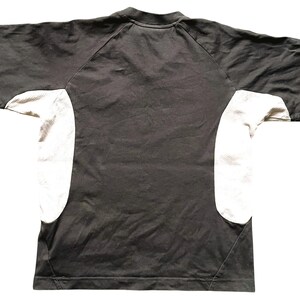 May include: A black and white t-shirt with a raglan sleeve design. The sleeves are white and the body of the shirt is black.