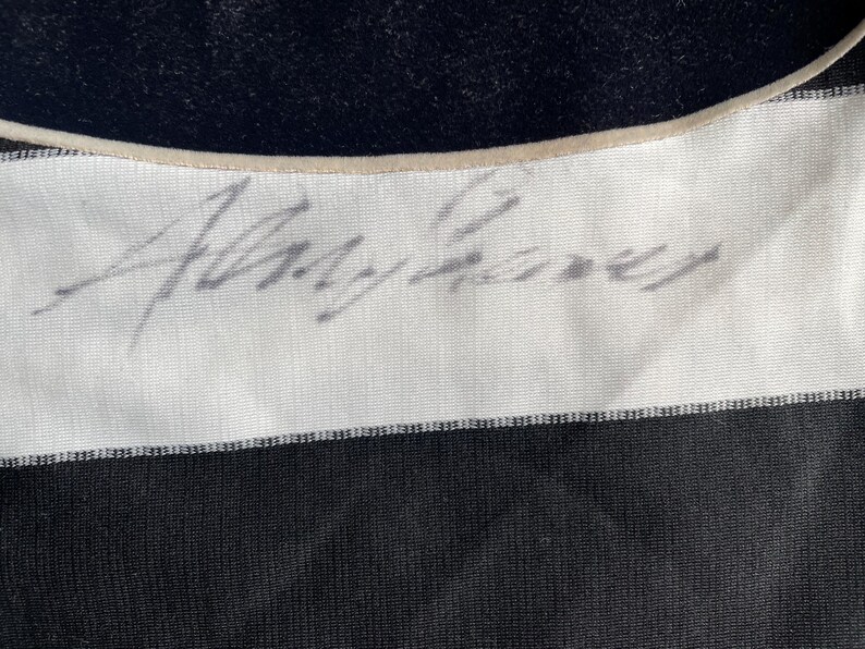 Puede incluir: Una camisa a rayas blancas y negras con una firma manuscrita que dice "Alvy Singer" en la secci&oacute;n blanca de la camisa.