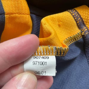 May include: Close-up of a white tag with black text. The tag reads "907409 971001 06/01".
