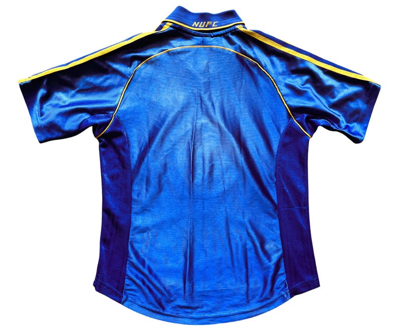 K&ouml;nnte beinhalten: Ein blaues Fu&szlig;balltrikot mit gelben und violetten Akzenten. Das Trikot tr&auml;gt den Text "NUFC" auf der R&uuml;ckseite.