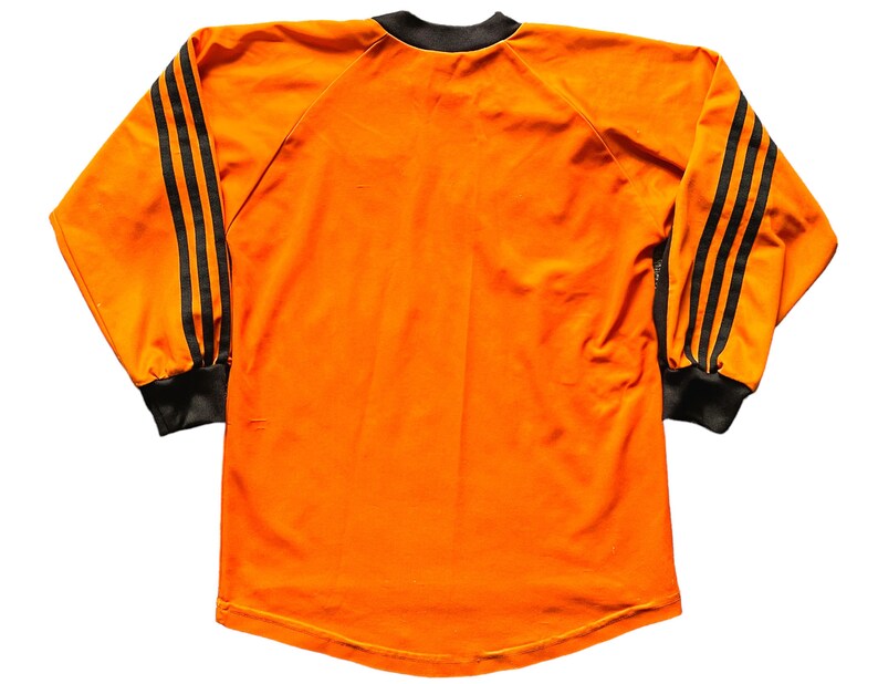 May include: Orange long-sleeved shirt with black stripes on the sleeves.