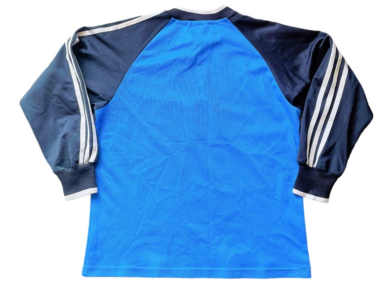 May include: A blue long-sleeved shirt with black and white striped sleeves. The shirt has a crew neck and is made of a soft, comfortable material.