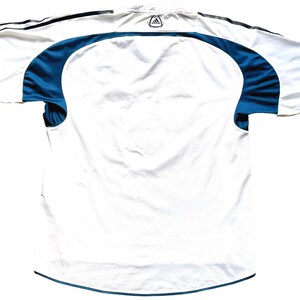 May include: White football shirt with teal blue accents on the sleeves and collar. The Adidas logo is visible on the back of the shirt.