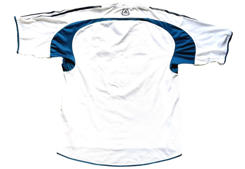 May include: White football shirt with teal blue accents on the sleeves and collar. The Adidas logo is visible on the back of the shirt.