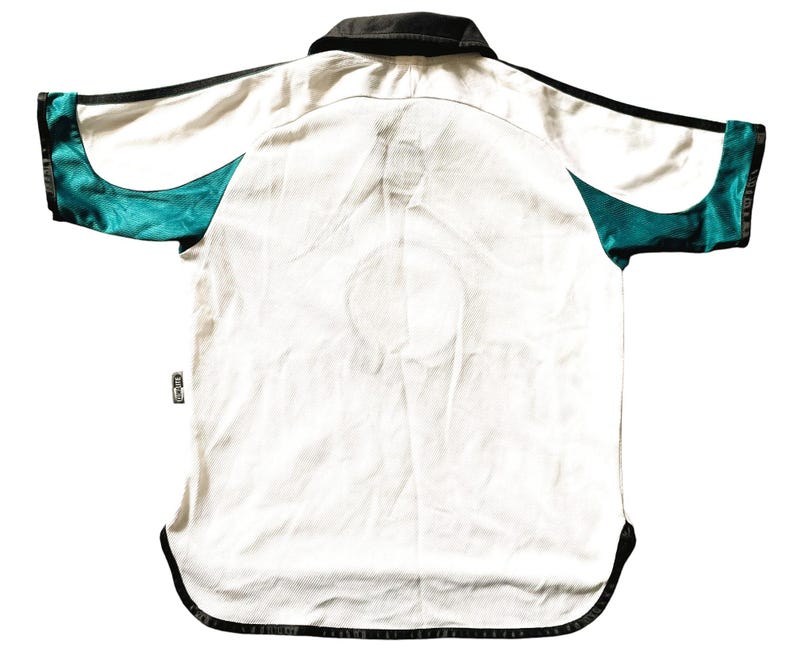 Pu&ograve; includere: Maglia da calcio a maniche corte bianca con dettagli neri e turchesi. La maglia ha un colletto nero e una striscia nera su ogni manica.