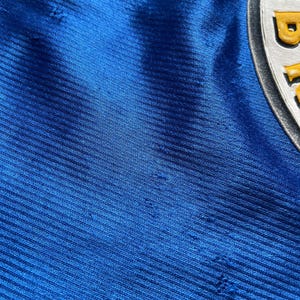 K&ouml;nnte beinhalten: Nahaufnahme eines blauen Stoffes mit einem strukturierten Muster. Der Stoff hat mehrere kleine L&ouml;cher.