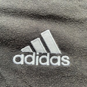May include: A close-up of a gray t-shirt with a white embroidered Adidas logo.