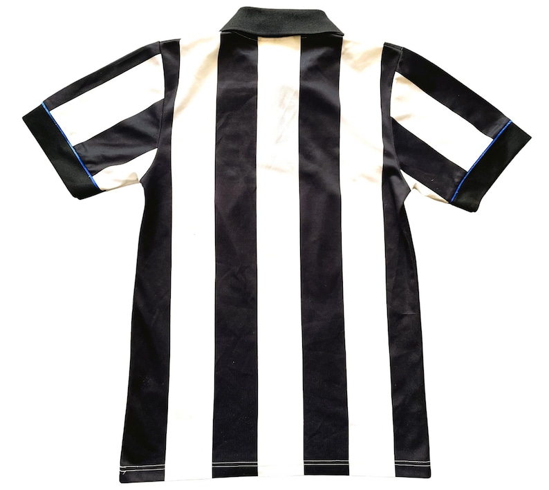May include: A short-sleeved collared shirt with vertical black and white stripes. The shirt has a black collar and sleeve trim with a thin blue accent. The garment is made of a smooth, possibly synthetic fabric.