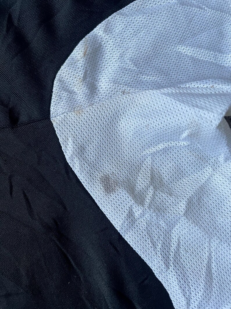 May include: Close-up of a black and white fabric with a mesh texture. The white fabric has a slightly textured surface.
