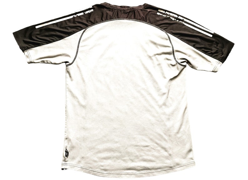 May include: A white short-sleeved t-shirt with black and white stripes on the shoulders. The shirt has a crew neck and a relaxed fit.