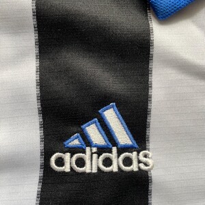 May include: A white and black striped soccer jersey with a blue and white Adidas logo embroidered on the front.