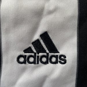 May include: A white and black striped athletic jersey with the Adidas logo and the word "adidas" in black.