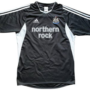 May include: Black and white soccer jersey with the Adidas logo, a team crest, and the text "northern rock" on the front.