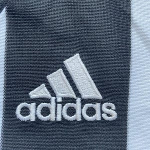 May include: White adidas logo embroidered on a black fabric background.