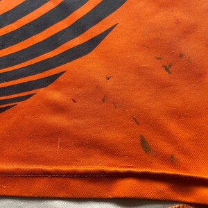 May include: Orange fabric with black stripes and several dark brown stains.