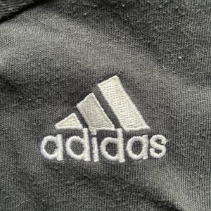 May include: A black Adidas logo with white stitching on a black fabric background.