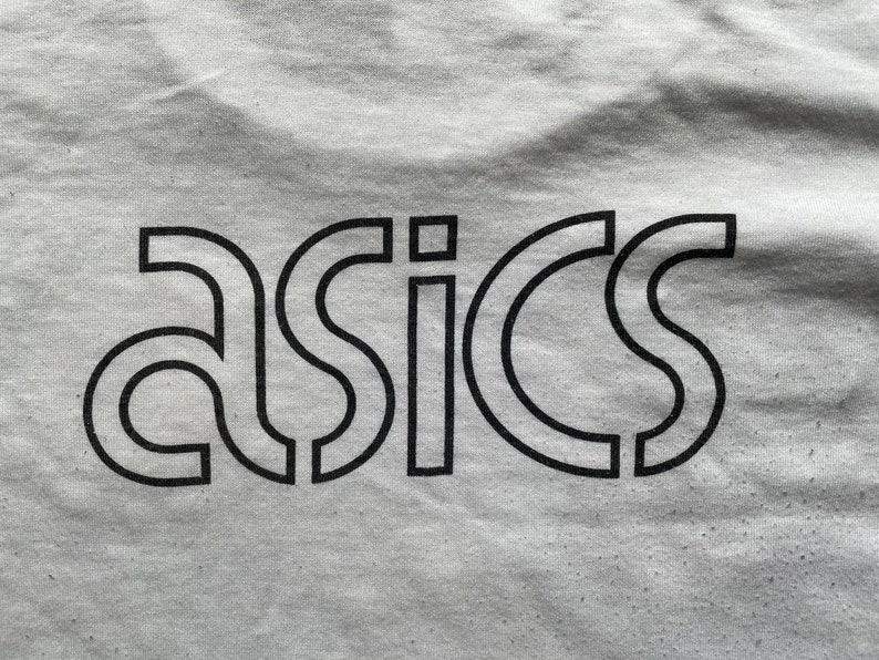 May include: A white t-shirt with a black "ASICS" logo printed on the front.