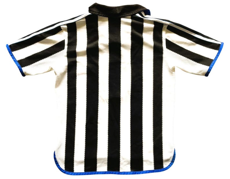 May include: A black and white striped referee shirt with a black collar and blue trim. The short-sleeved shirt has a mesh-like texture and is viewed from the back. The stripes are vertical and evenly spaced.