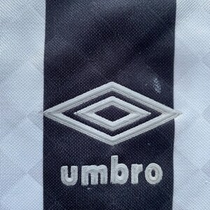 May include: A black and white striped soccer jersey with a white diamond logo and the word "umbro" in white lettering.
