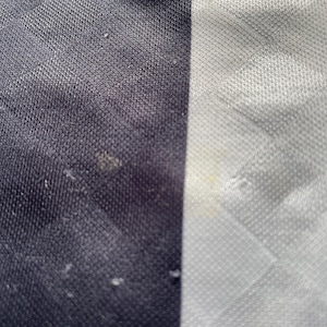 May include: Close-up of a black and white striped fabric. The fabric has a textured, woven appearance.