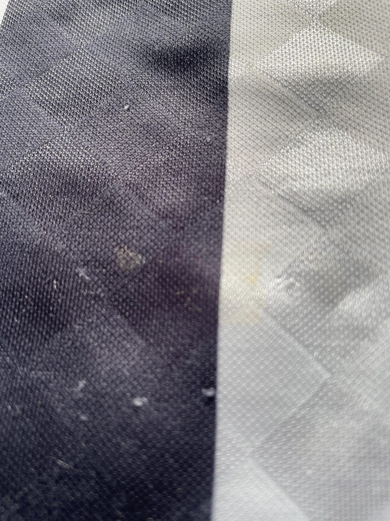 May include: Close-up of a black and white striped fabric. The fabric has a textured, woven appearance.