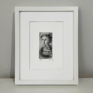 May include: A black and white framed print of a portrait of a person. The print is signed and numbered 2/20. The print is titled "03/11/94".