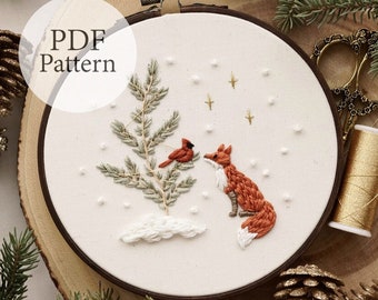 May include: Embroidered hoop art featuring a fox looking at a cardinal perched on a pine branch. The background is white with gold stars and white dots. The text "PDF Pattern" is in a white circle at the top of the image.