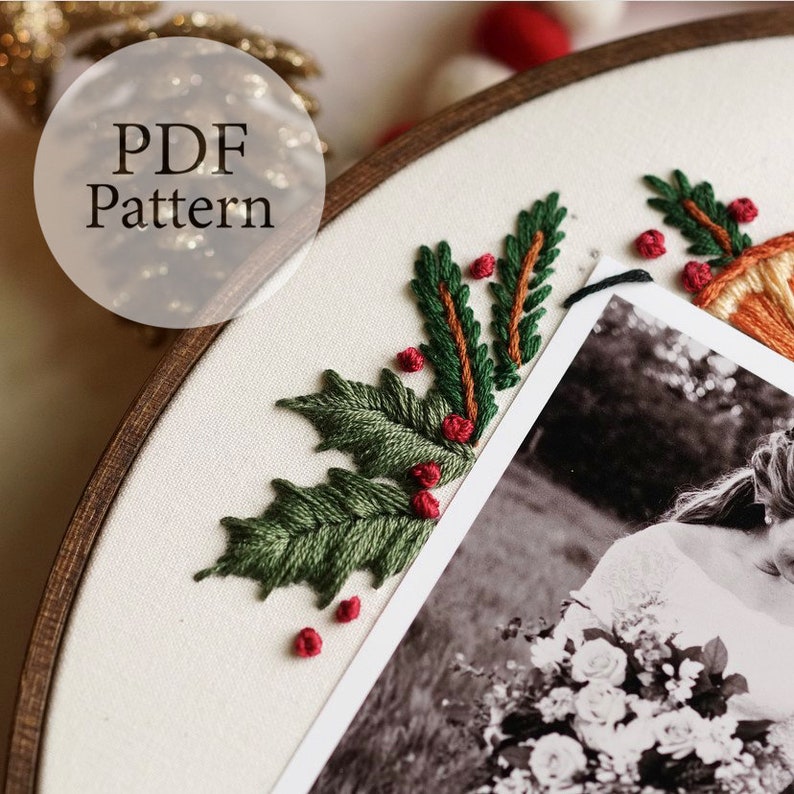 May include: A close-up of a white fabric with green and red embroidery of holly leaves and berries. A black and white photo is partially visible in the background.