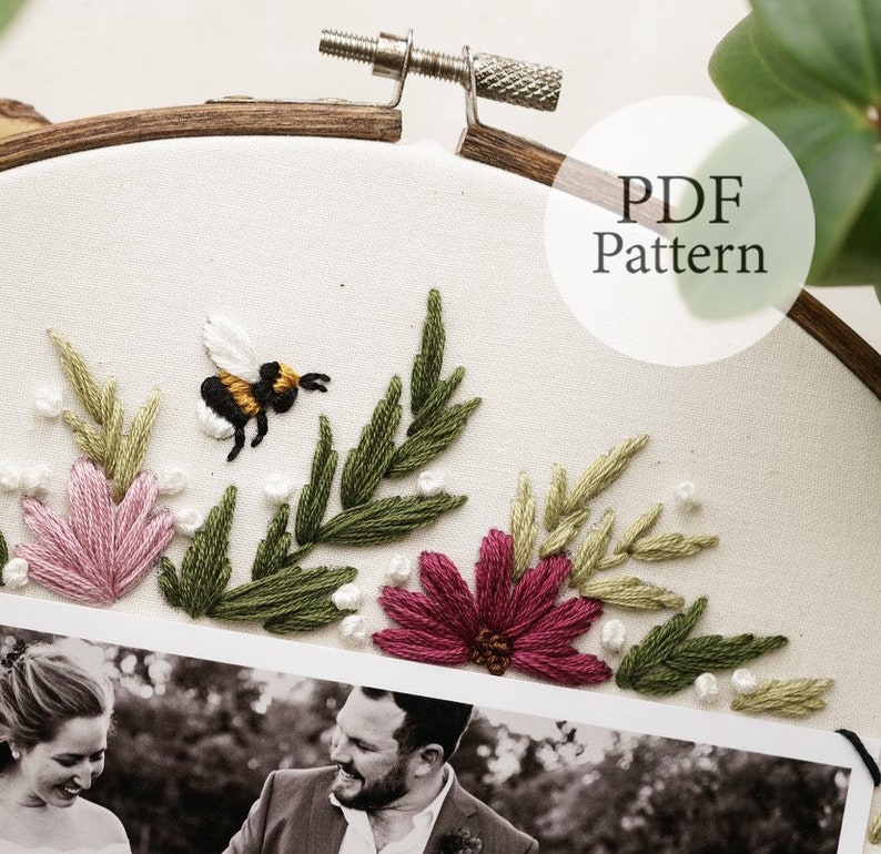 May include: Embroidered hoop art featuring a black and yellow bee, pink and green flowers, and green leaves. A black and white photo of a couple is at the bottom of the hoop. The text "PDF Pattern" is in the upper right corner of the image.