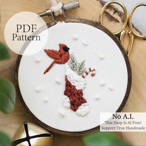 May include: Embroidered Christmas ornament featuring a red cardinal and a stocking with a candy cane. The design is set in a wooden embroidery hoop. The text "PDF Pattern" and "No A.I. This Shop Is AI Free! Support True Handmade" are visible.