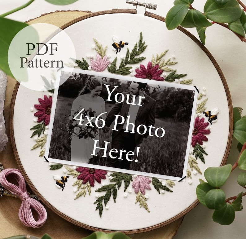 May include: Embroidered hoop art with a floral design in shades of pink, green, and burgundy. The hoop features a 4x6 photo space with the text "Your 4x6 Photo Here!" and two small embroidered bees.